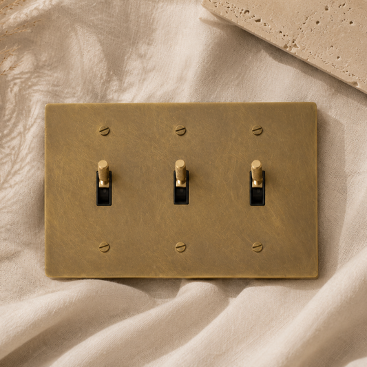 Triple solid brass toggle light switch with a brushed finish.