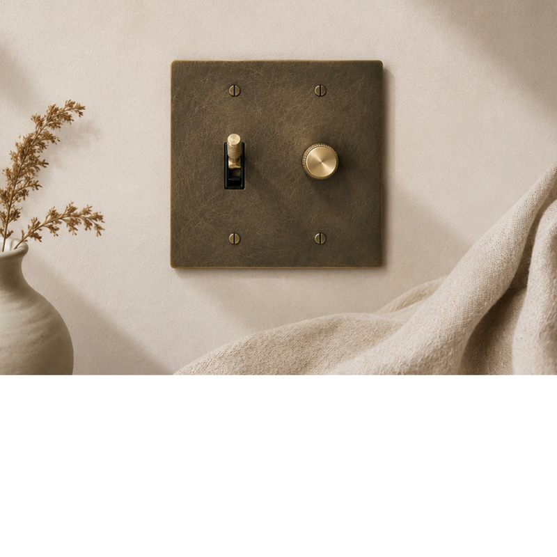 Solid brass light switches in a warm, modern interior with natural materials and soft lighting.