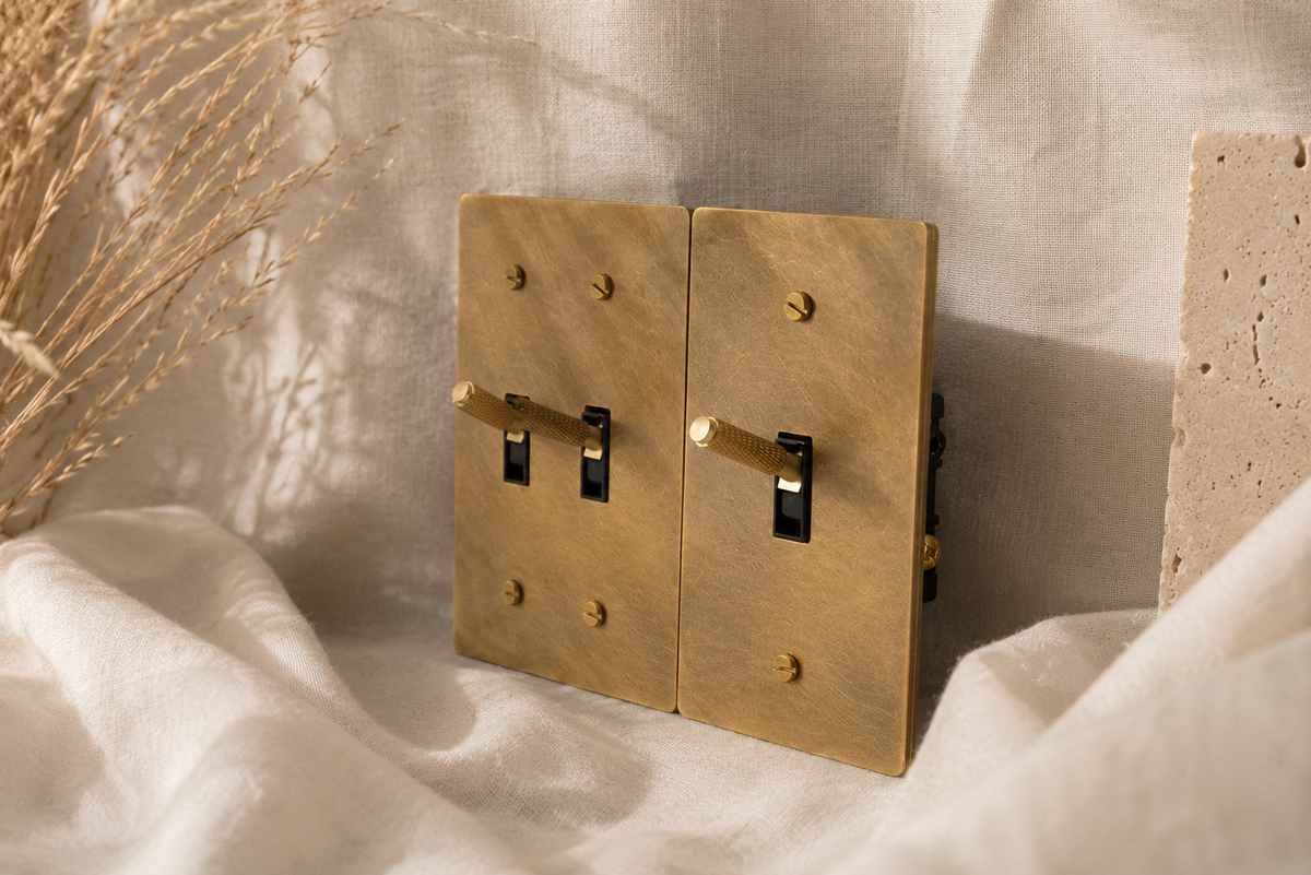 Solid brass light switches in a warm, modern interior with natural materials and soft lighting.