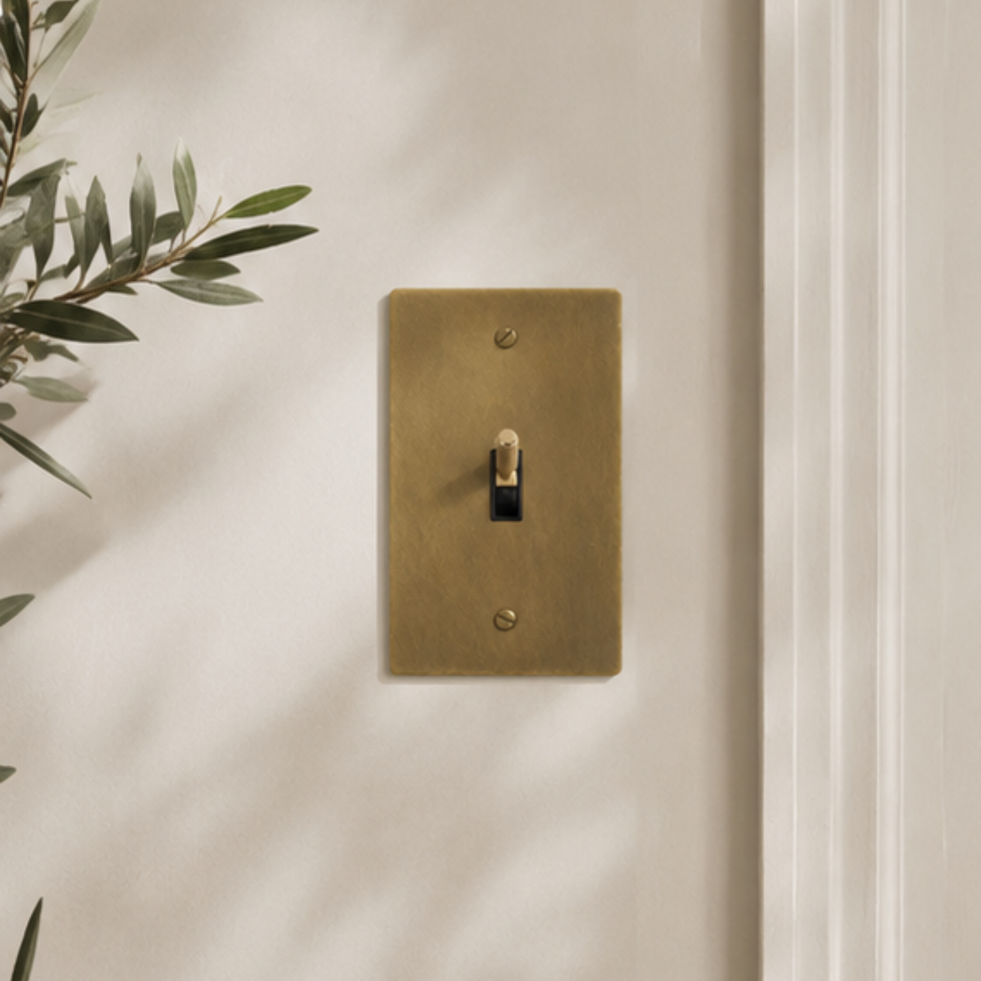 Solid brass light switches in a warm, modern interior with natural materials and soft lighting.
